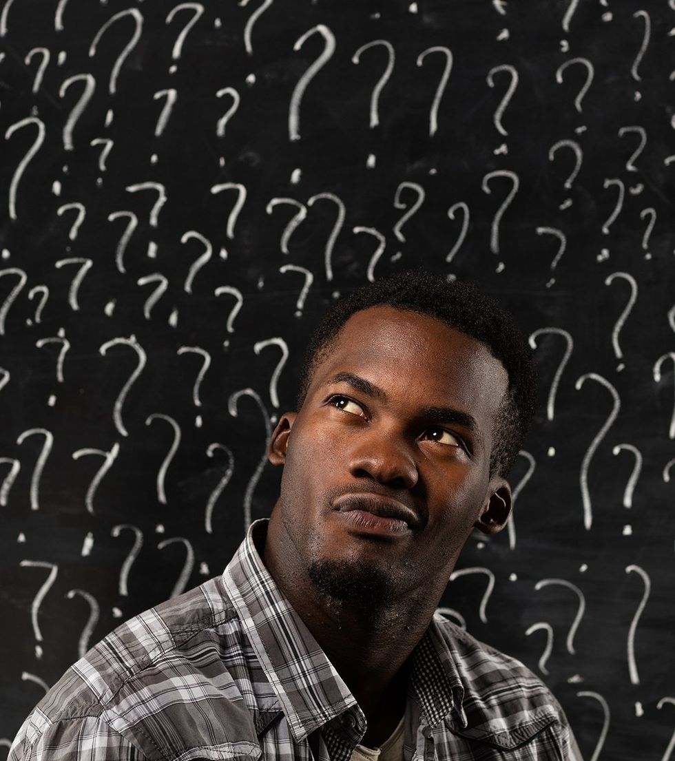 handsome black man in front of chalkboard full of question marks making tough decision concept