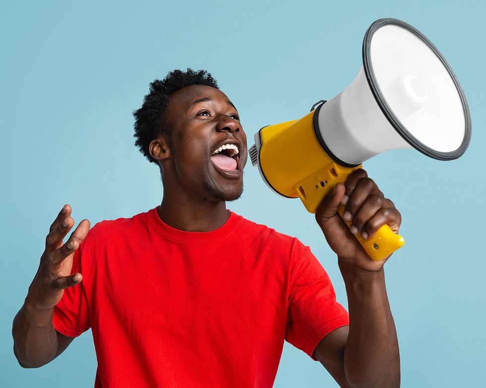 happy handsome black man with red shirt and megaphone against a blue background