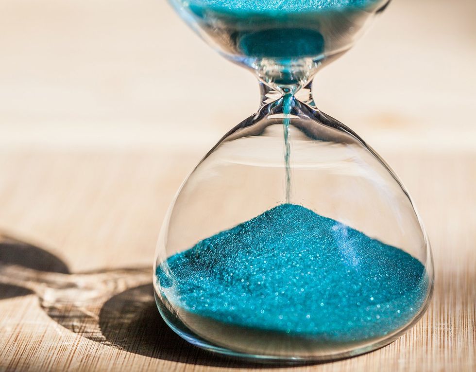 hourglass with teal sand on a wood table