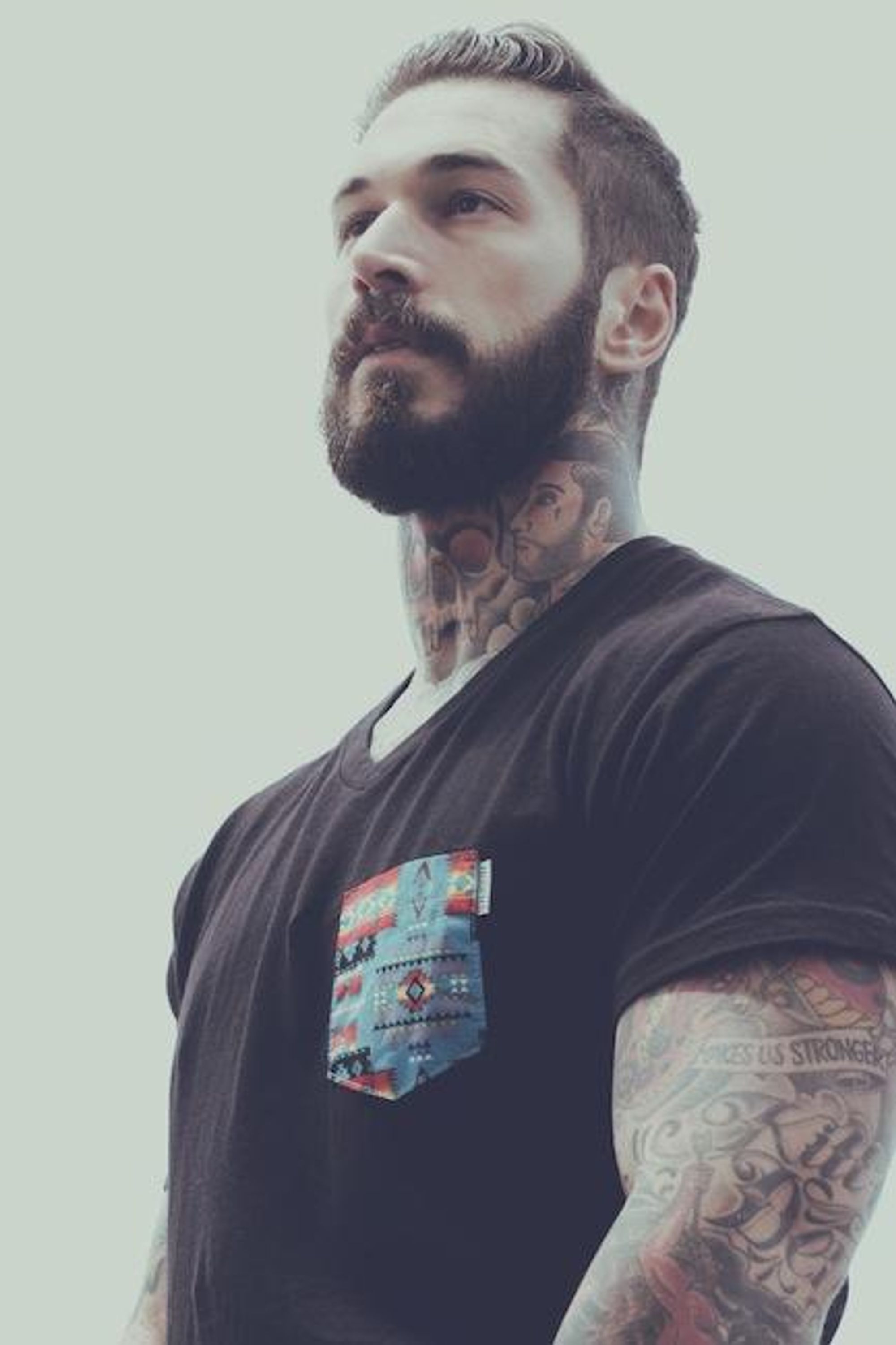 A separate black-and-white Alex Minsky editorial portrait showing face, neck and chest tattoos