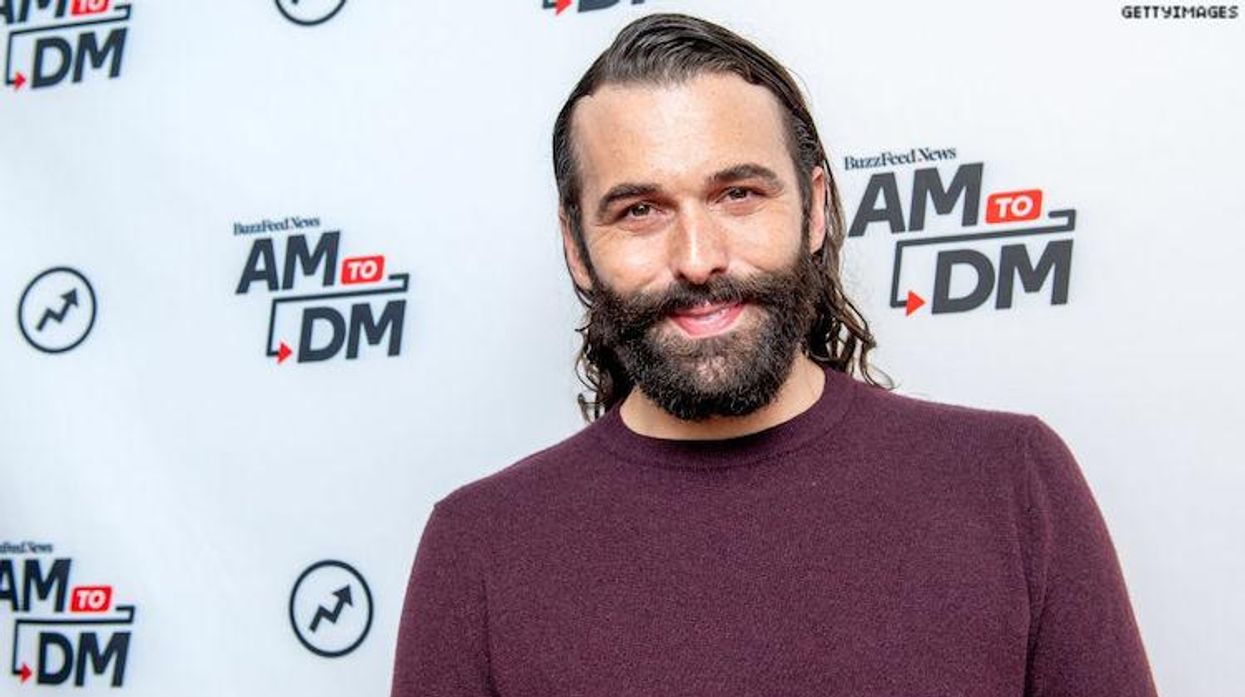 Jonathan Van Ness standing in front of a step and repeat, smiling.