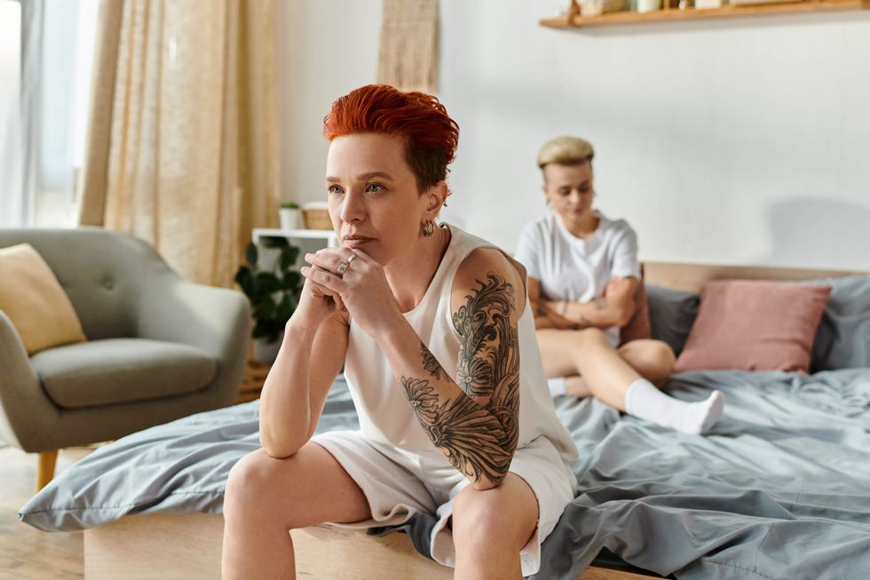 Lesbian couple sitting in bed looking away from each other