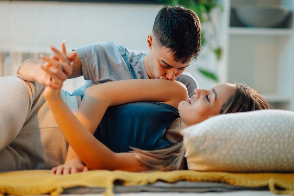 Lesbian lying in bed, spooning and holding hands