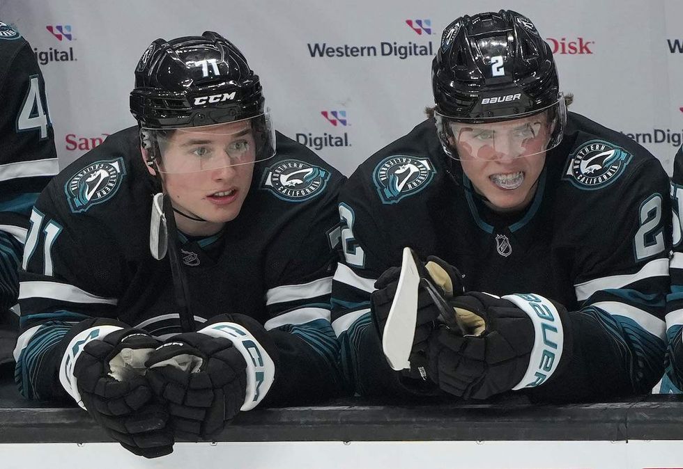 Macklin Celebrini #71 and Will Smith #2 of the San Jose Sharks look on from the bench against the Tampa Bay Lightning