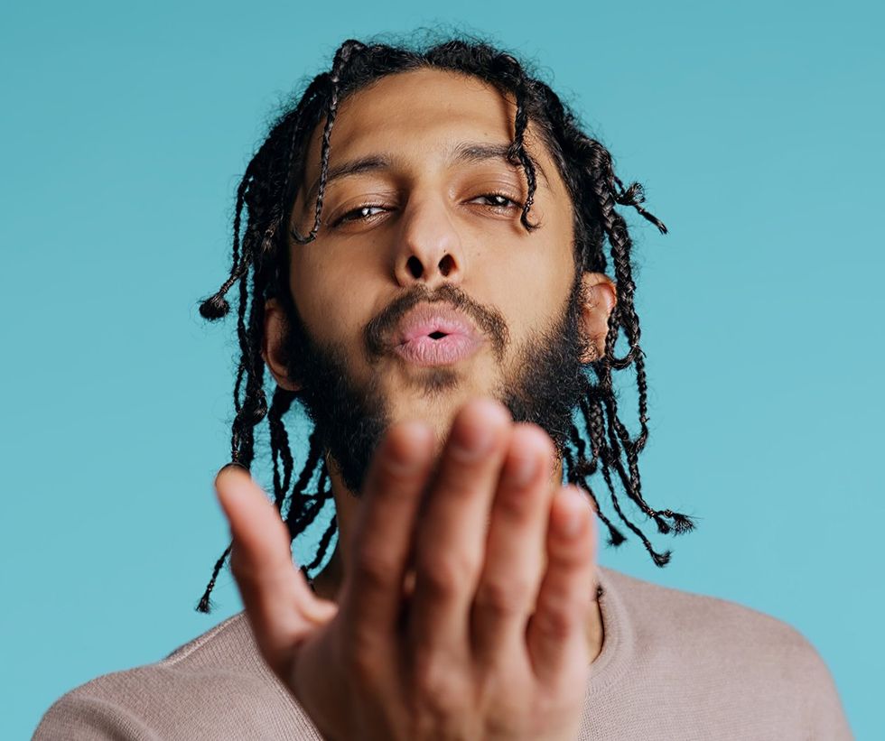 man extending hand toward viewer blowing air or kiss