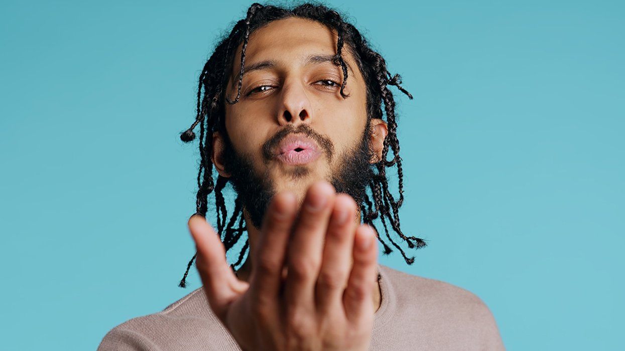 man extending hand toward viewer blowing air or kiss