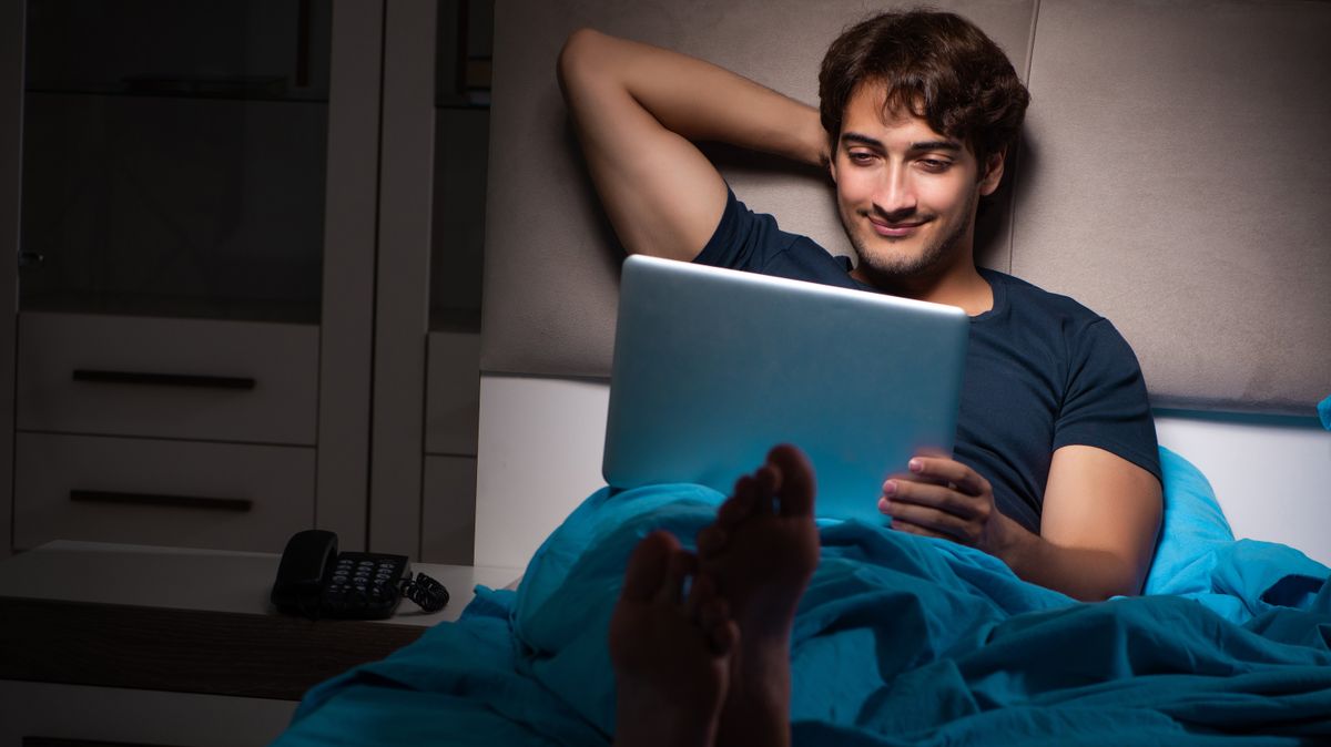 Man in bed looking at his laptop