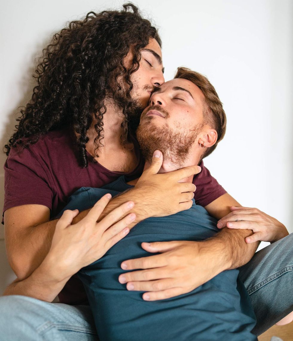 Man kissing another man he's holding on the forehead