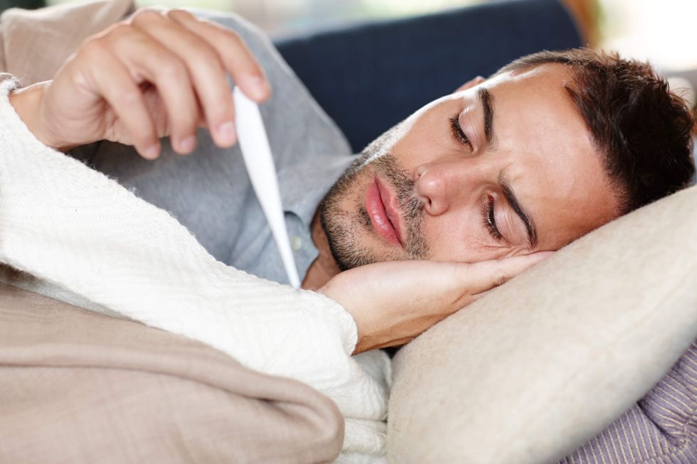 Man lying down and holding a thermometer