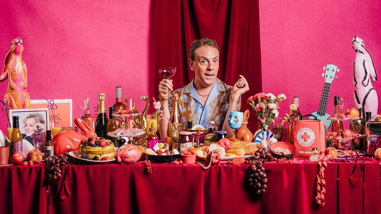 MESSY WHITE GAYS show Drew Droege at the center of a long feast table full of lavish colorful stage props