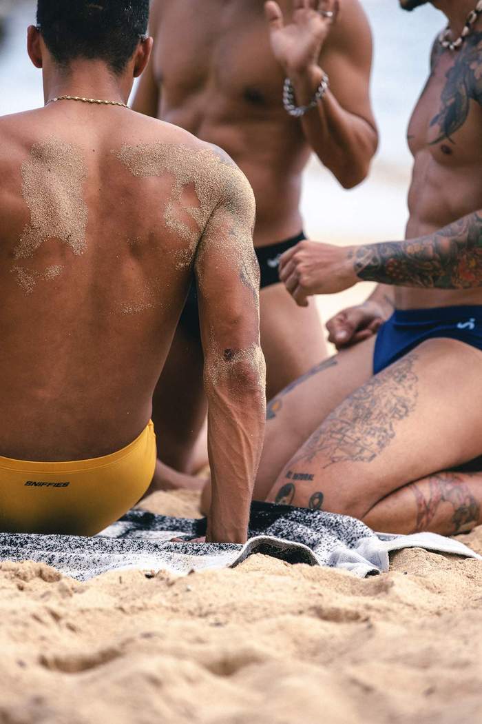 Models wearing Sniffies swim briefs gather together on the beach during the Sniffies Summer Swim Collection campaign in Puerto Rico.