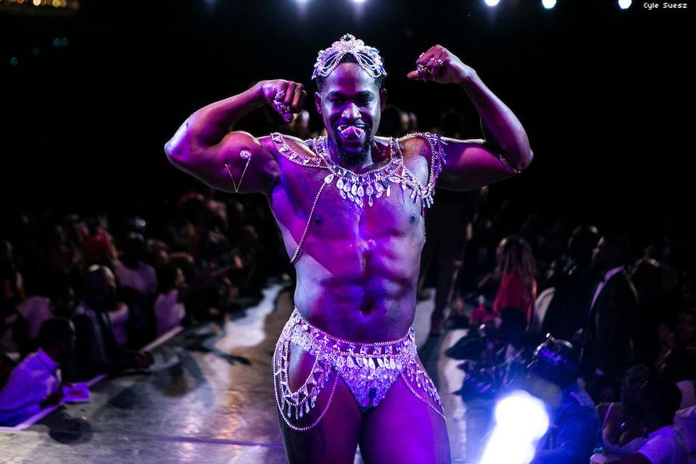 Muscular man flexing in a thong with crystals and charms on it.