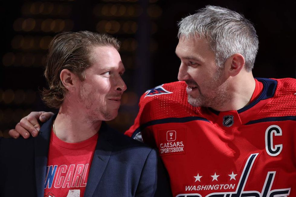 Nicklas Backstrom #19 of the Washington Capitals and Alex Ovechkin #8 of the Washington Capitals look at one another as John Carlson is acknowledged for playing in his 1000th NHL game