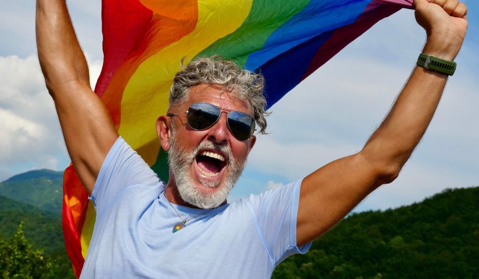Older gay man holding a Pride flag