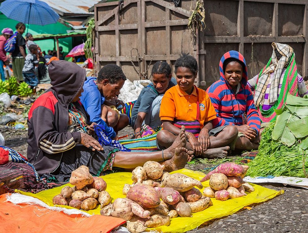 PAPUA NEW GUINEA WAMENA IRIAN JAYA Papuans woman sell sweet potatoes and other vegetables on the street market in Wamena New Guinea Indonesia
