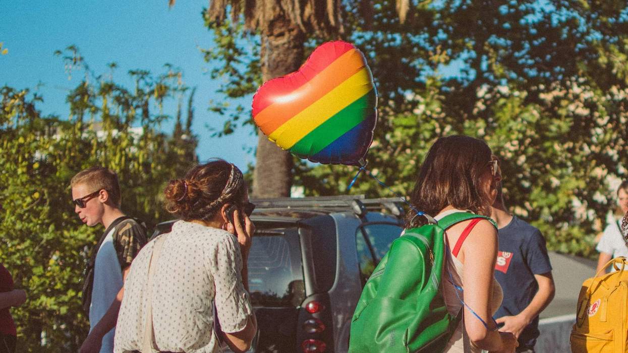People at an outdoor event with a heart-shaped rainbow balloon.