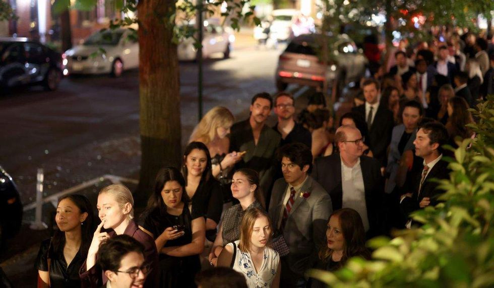 people stand in a long line outside the grindr whcd party