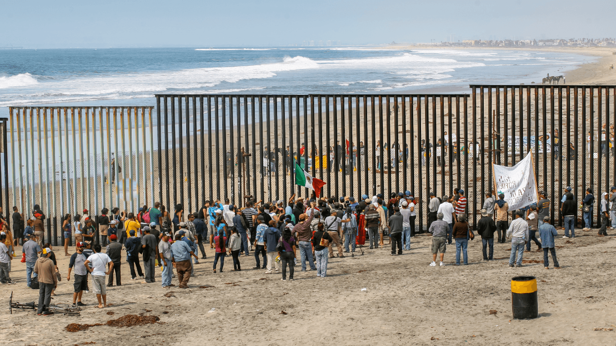 People stand on both sides of the border wall separating Tijuana and San Diego.