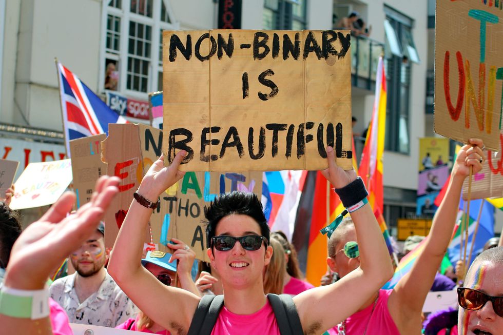 Person holding a 'Non-binary is beautiful sign.'