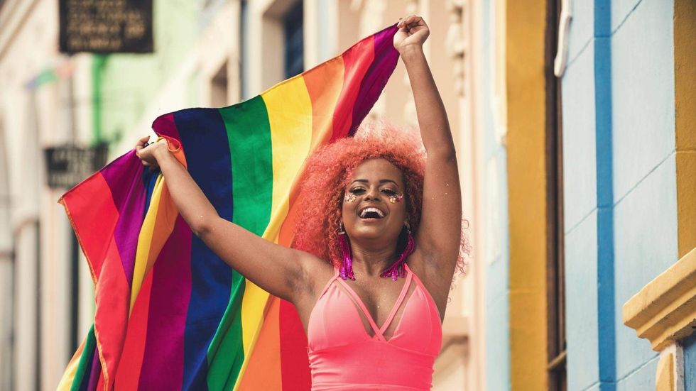 Person holding a rainbow Pride flag while celebrating at a festival in Malta.