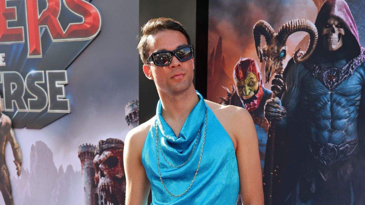 Person in sunglasses and blue top at a fantasy-themed event backdrop.