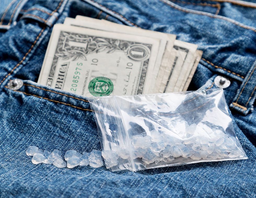 plastic bag with crystal rocks drug concept on jeans with cash showing in pocket