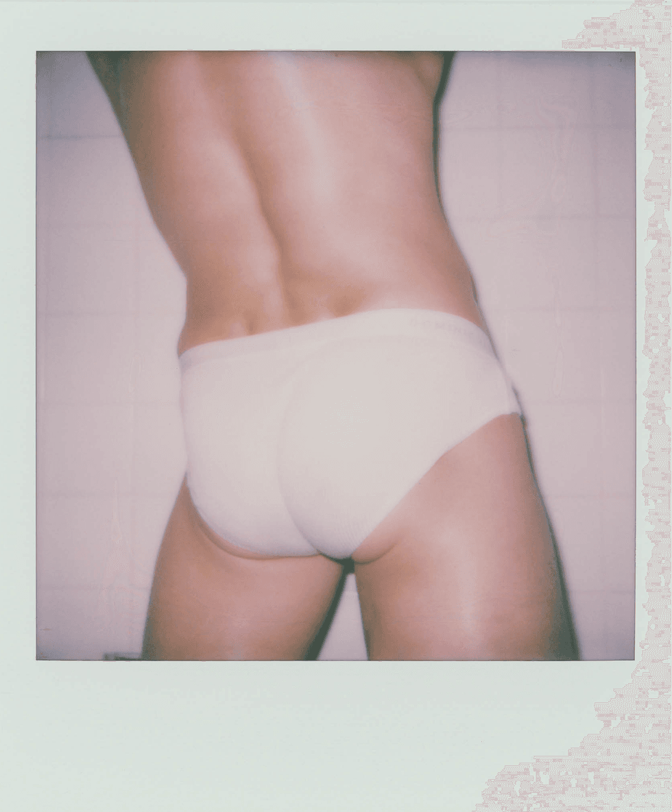 Polaroid close-up of a person\u2019s lower back and hips wearing briefs.