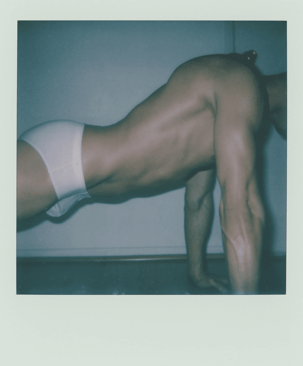 Polaroid image of a man lying sideways wearing white briefs.