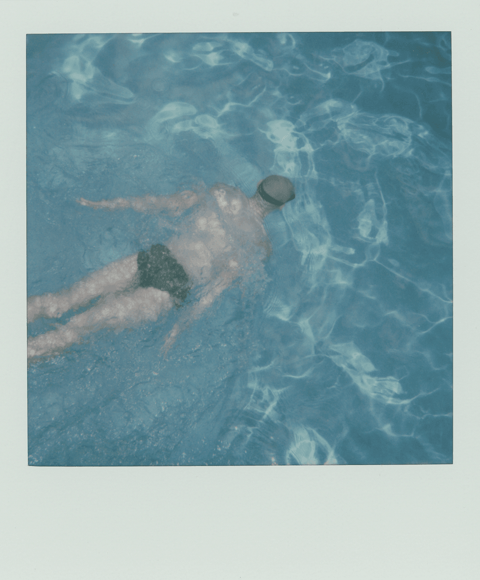 Polaroid image of a man swimming underwater in a pool.