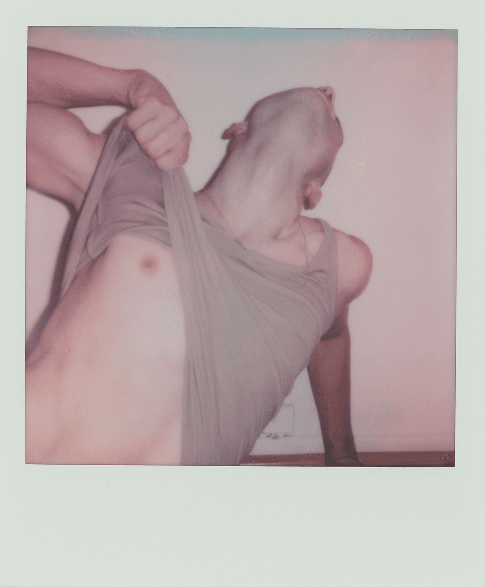 Polaroid portrait of a man leaning back while pulling up his tank top.