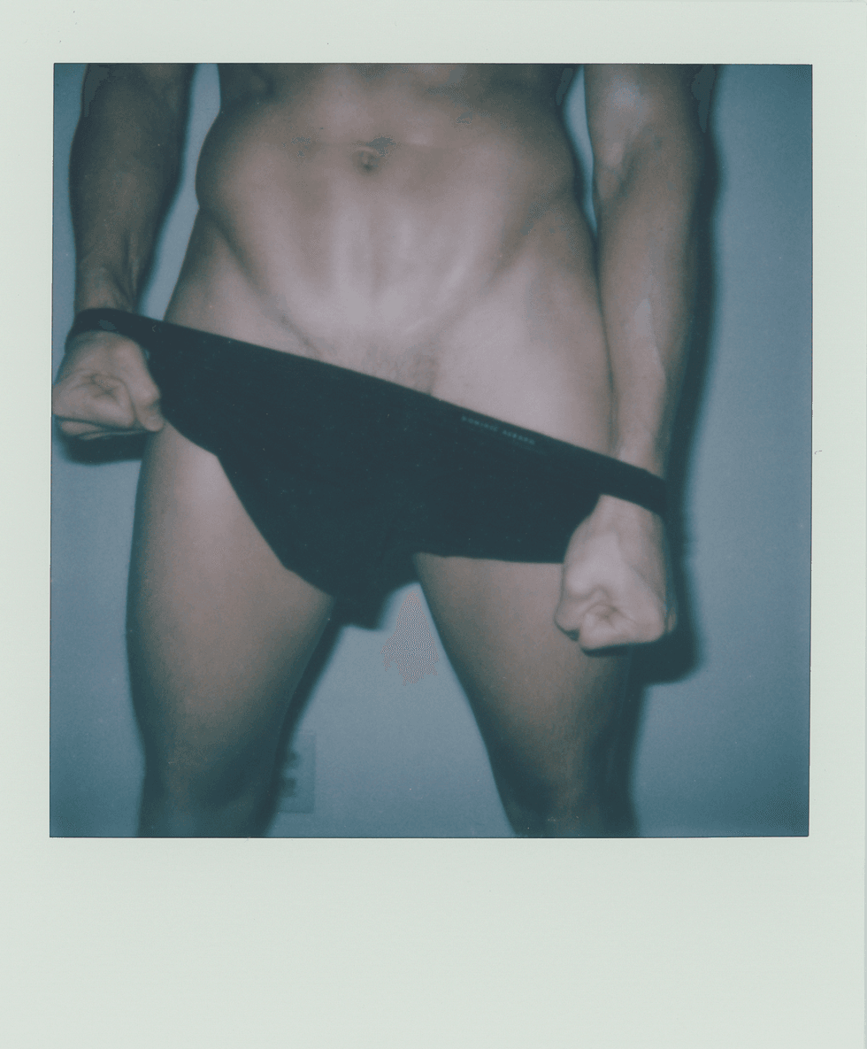 Polaroid portrait of a man pulling down dark briefs.