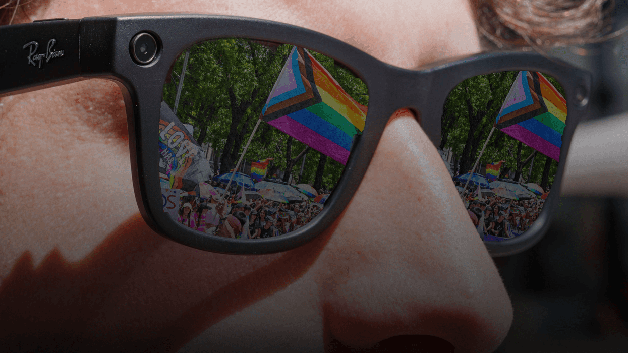 Pride flags and crowd reflected in sunglasses at an outdoor event.
