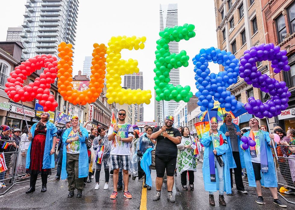 pride march with rainbow balloons spelling Queers