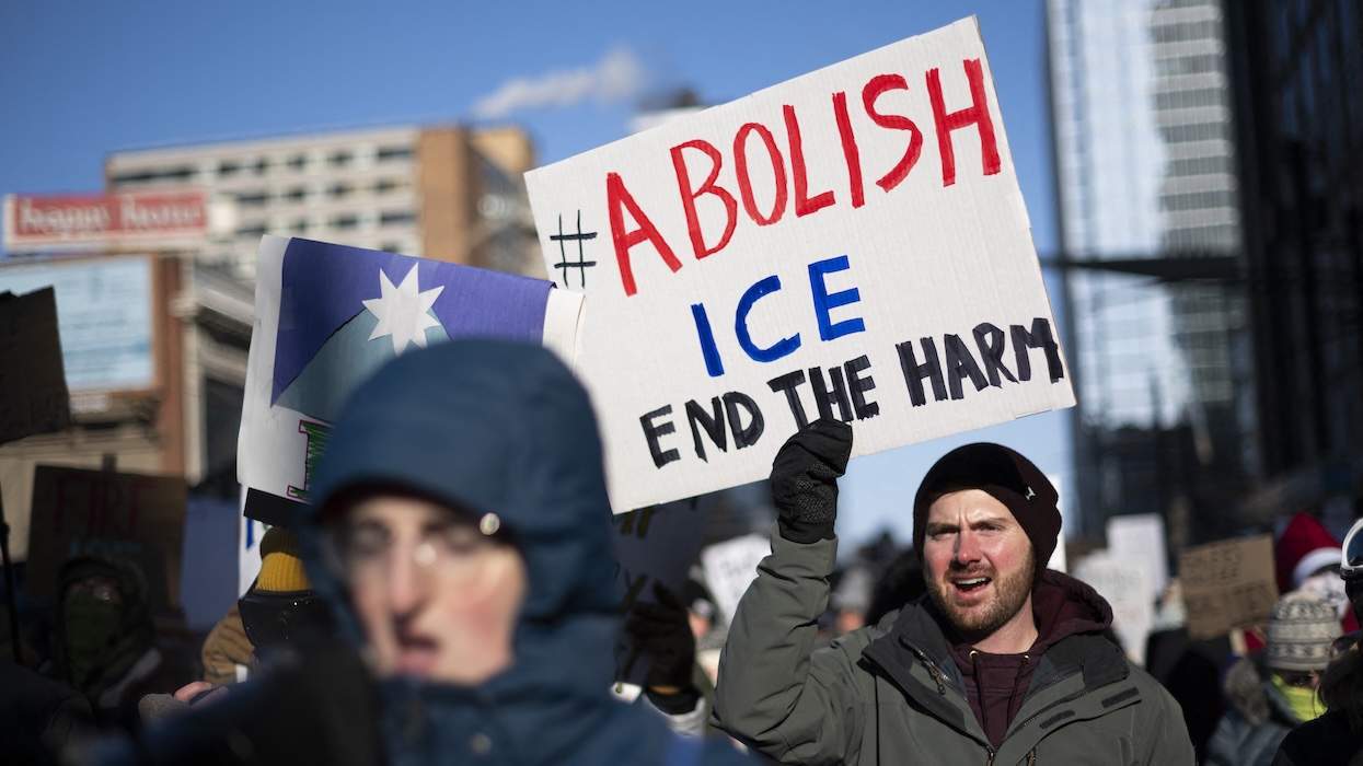 Protesters against Immigration and Customs Enforcement (ICE) march through the streets of downtown Minneapolis. One holds a placard that reads: Abolish ICE, end the harm.