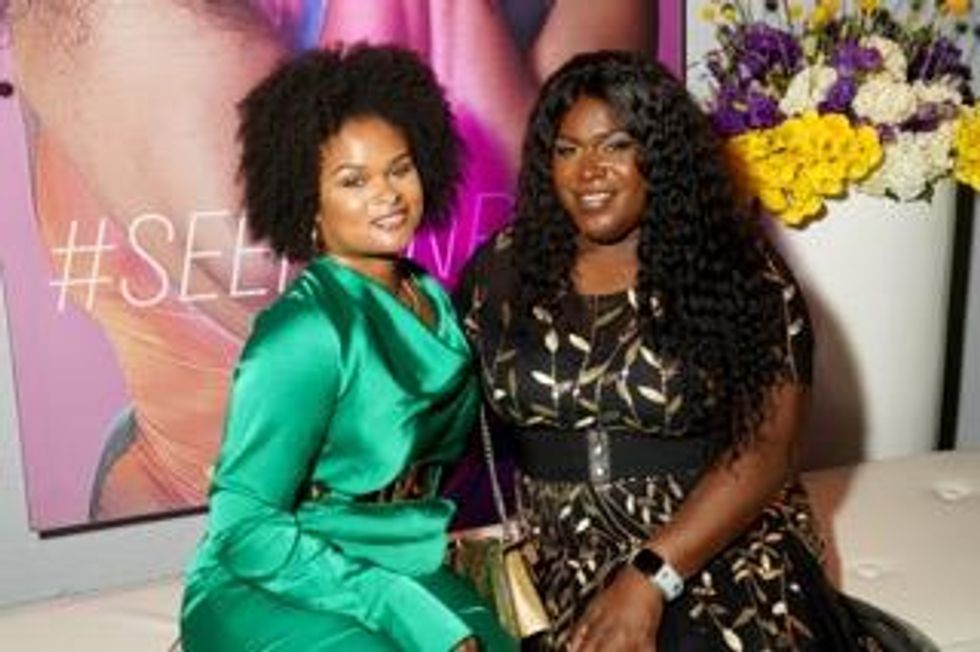 Queer women sitting together in front of an Out Magazine cover recreations