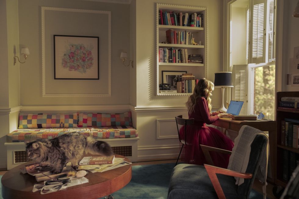 Sarah Jessica Parker as Carrie Bradshaw sitting at a desk, typing on a laptop