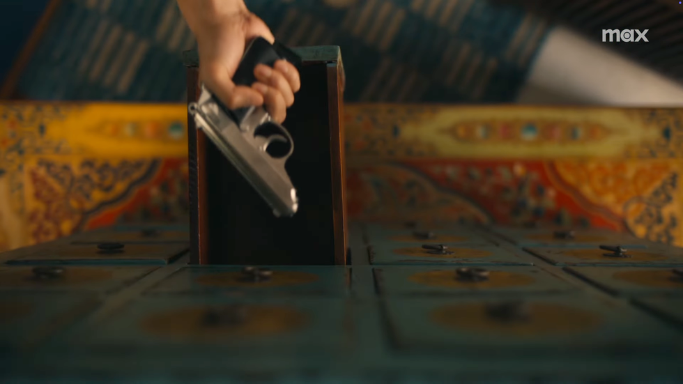 Scene featuring a hand holding a gun in The White Lotus season 3 trailer.