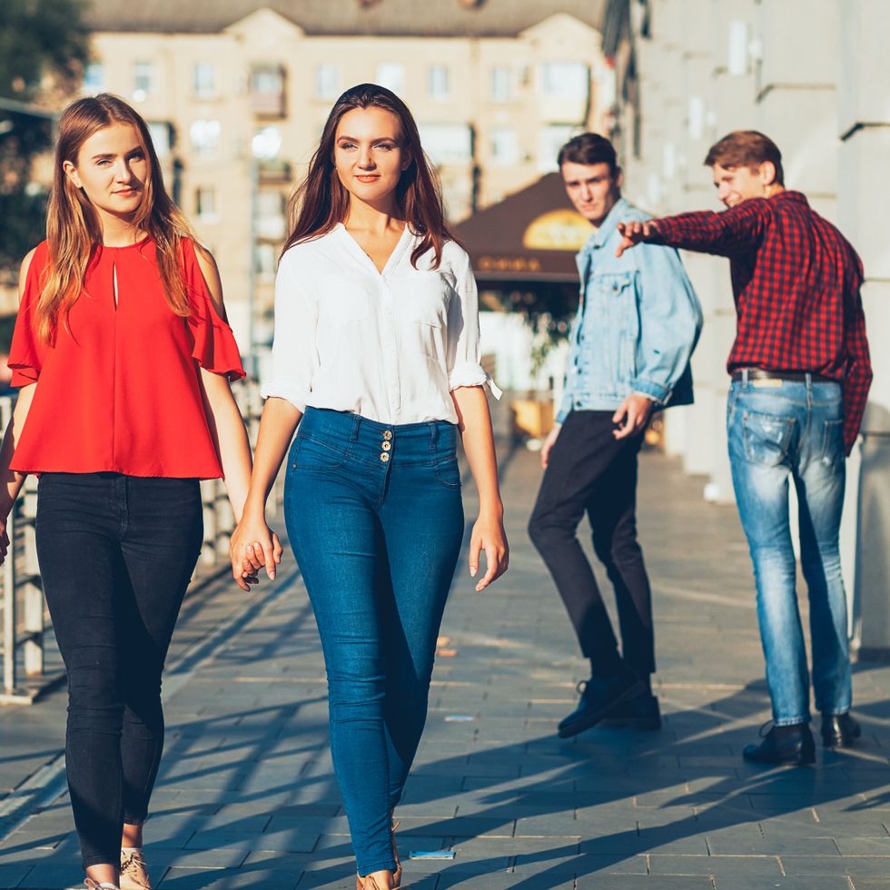 Sexual tolerance. Judgement mockery shame. Men staring at lesbian women walking holding hands.