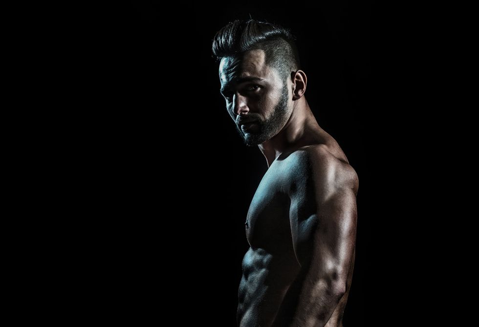 shirtless man from the side in shadow looking at the camera