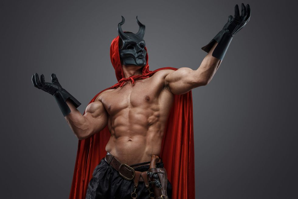 Shirtless man in a devil costume with a mask