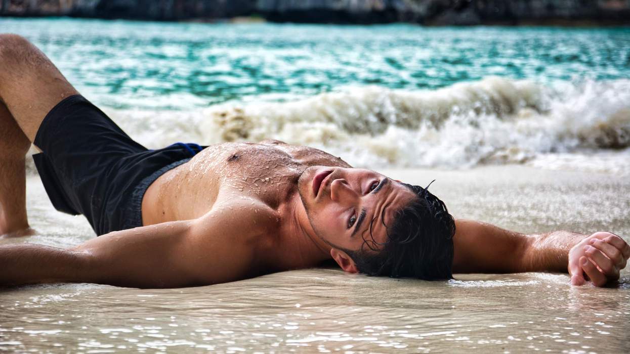 Shirtless man lying on the beach on his back