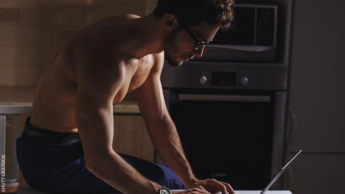 Shirtless man on laptop.