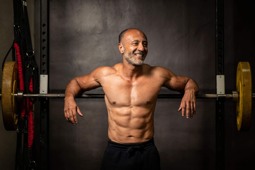 Shirtless older man leaning against a bench press