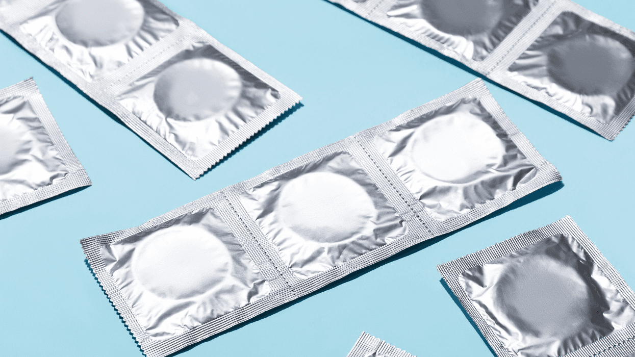 Silver foil-wrapped condoms arranged on a light blue background