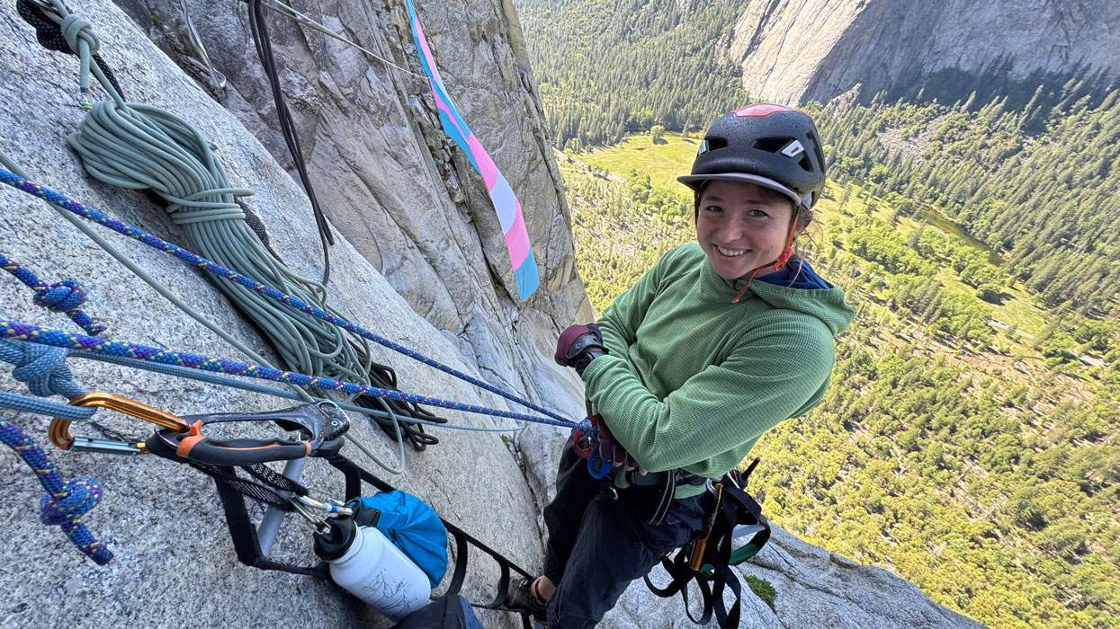 ​SJ Joslin smiles on El Capitan summit with giant transgender pride flag hanging in background