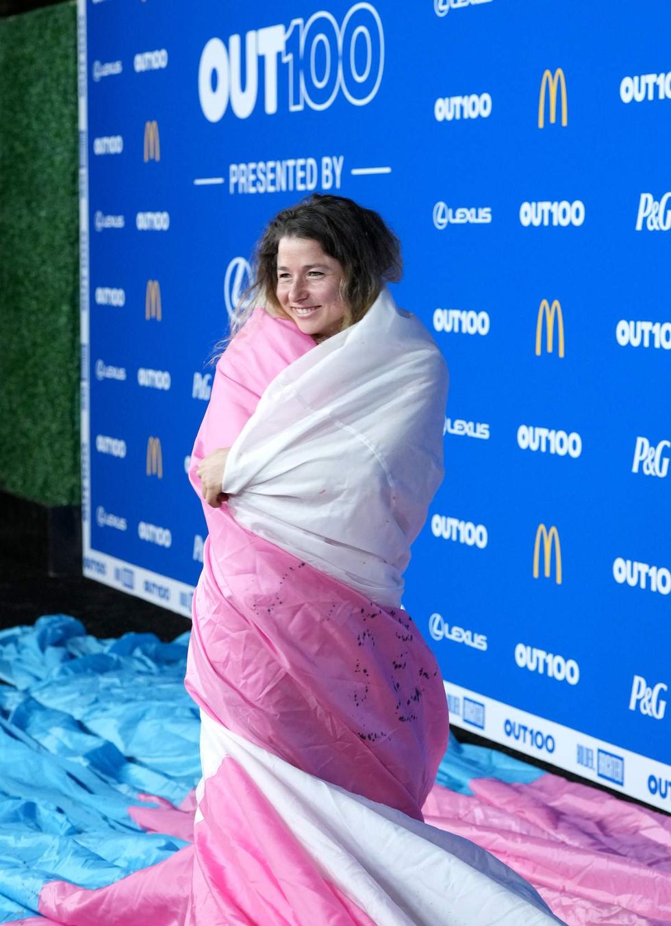 SJ Joslin wrapped in the trans flag on the 2025 Out100 red carpet