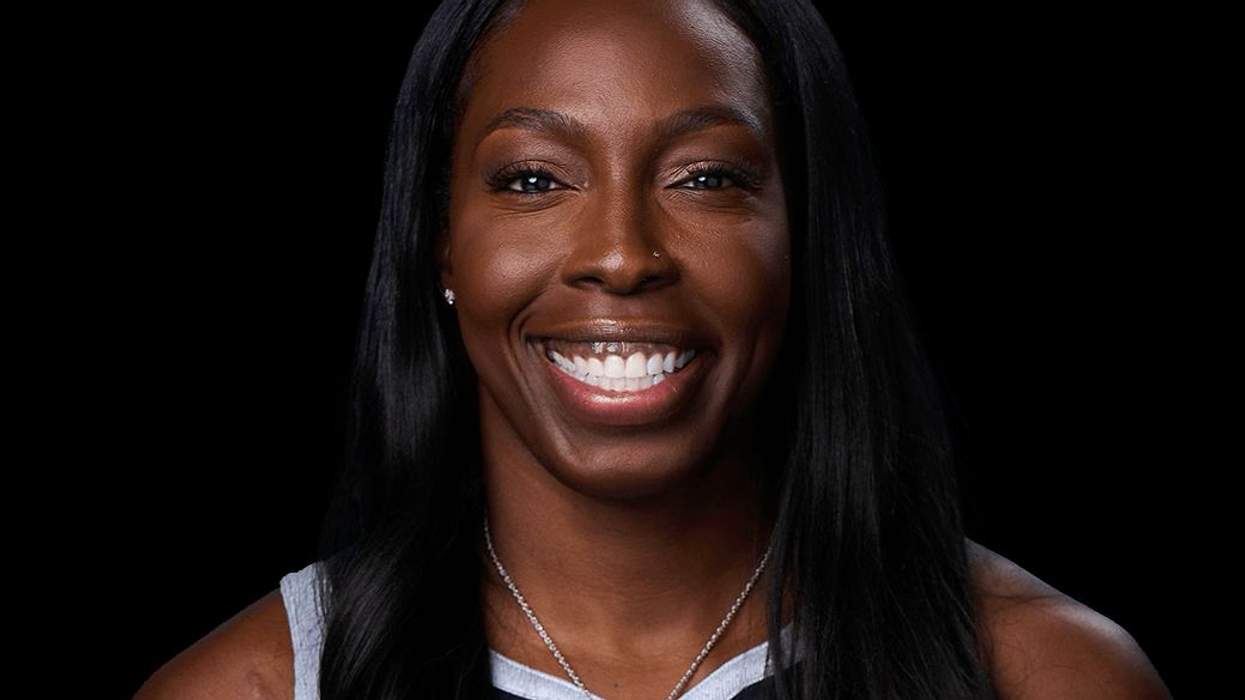 Smiling woman with long black hair, wearing a sports jersey, against a black background.