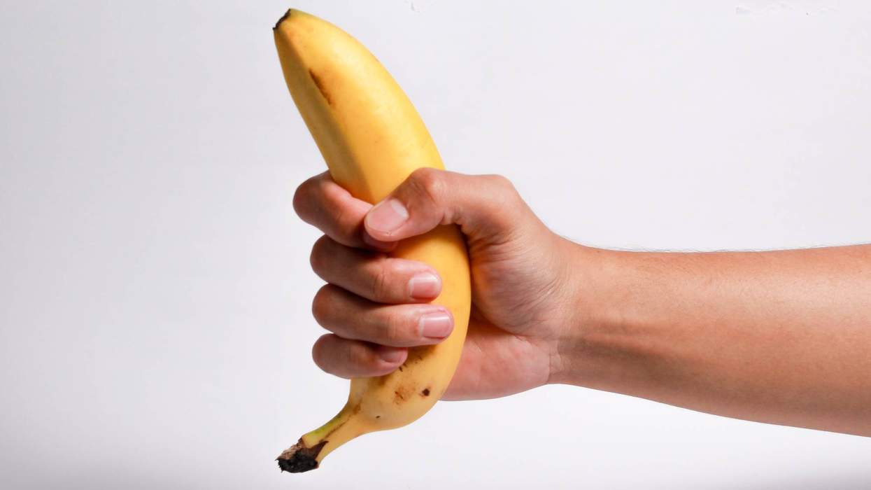 Someone gripping a banana, to represent how to give a hand job