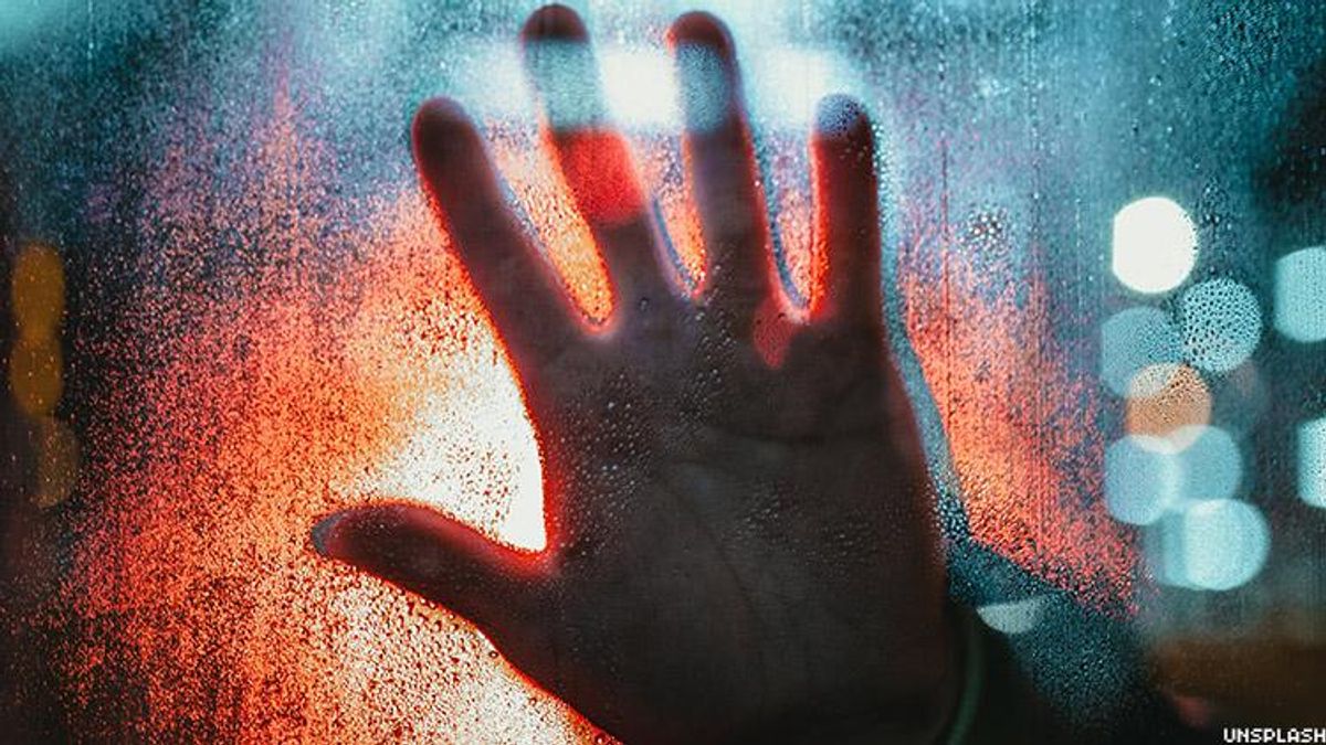 Stock photo of a hand against a window.