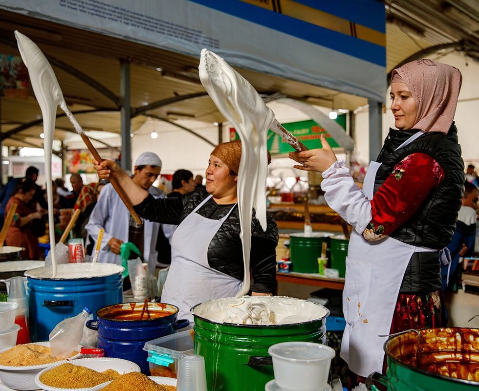 Tashkent Uzbekistan vendors stretch traditional sticky sweets nisholda white jam in a bustling market Uzbek culinary culture Sweet food during Ramadan